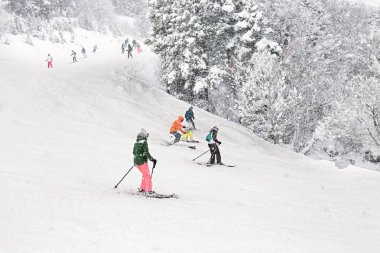 Yoğun kar yağışı sırasında Kayak yokuş aşağı. Turistler, yetişkinler ve çocuklar, Andorra resort yamaçta Grup.