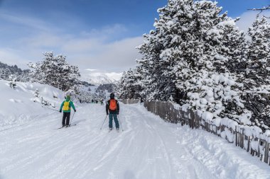 Pyrenees, Andorra - 6 Şubat 2018: Bilinmeyen turist kayaklar üzerinde kayak pisti üzerinde aşağı in. Pitoresk çam ağaçları kar ve dağlar mesafe üst kısımları. Güneşli kış günü, frost ve güneş