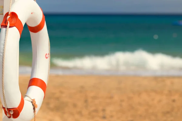 Lifebuoy sahilde. Kumlu deniz kıyısında arka plan üzerinde beyaz lifebuoy. Kavramı güvenli su eğlence için