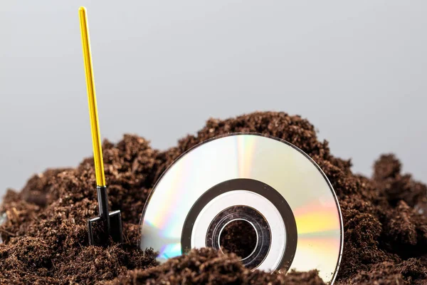 The CD is half buried in the ground, next to a shovel — Stock Photo, Image