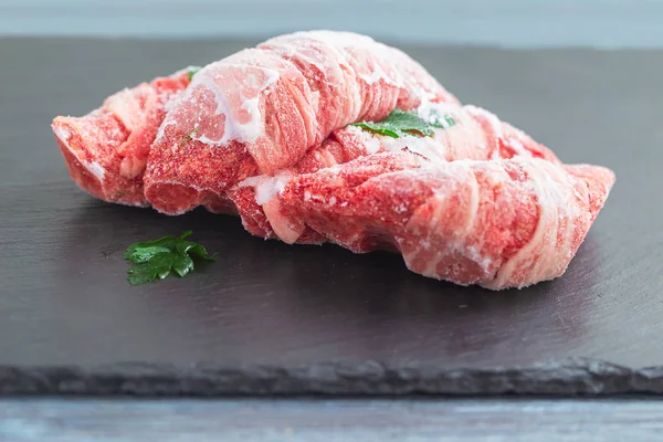 Frozen meat with parsley on a black slate board — Stock Photo, Image