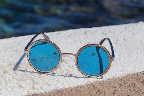 Óculos de sol redondos com óculos azuis na pedra . — Fotografia de Stock