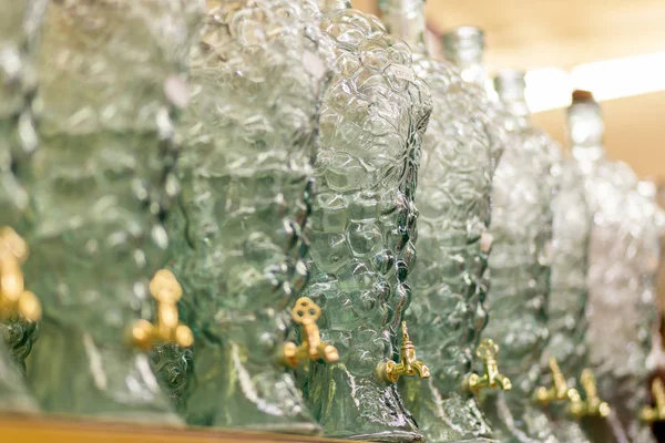 Une série de bouteilles en verre figuré avec robinets se trouvent sur l'étagère du magasin — Photo