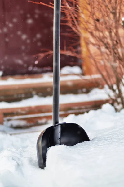 Pala da neve nella neve vicino alla casa — Foto Stock