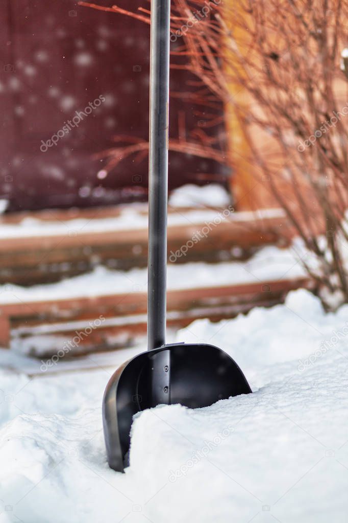 Snow shovel in the snow near the house