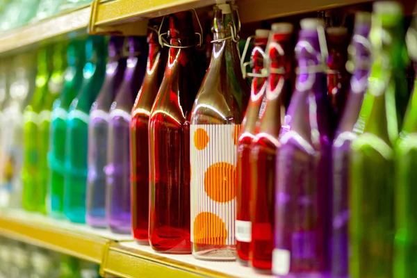 Veelkleurige glazen flessen op de plank in de winkel. — Stockfoto