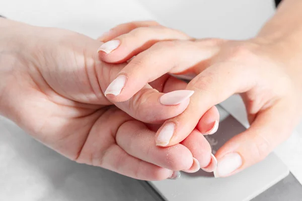 The hands of the master of the hardware manicure and the hands of the client close-up during the preparatory work.