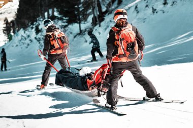 Rescuers at a ski resort evacuate the victim from the slope. clipart