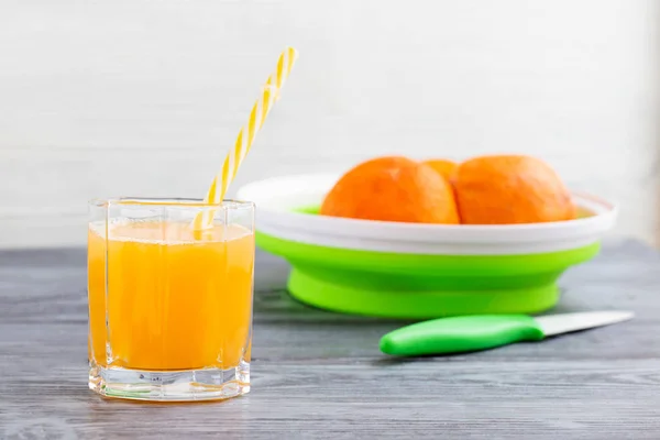 新鲜挤压的橙汁和橘子在灰色的木桌上. — 图库照片