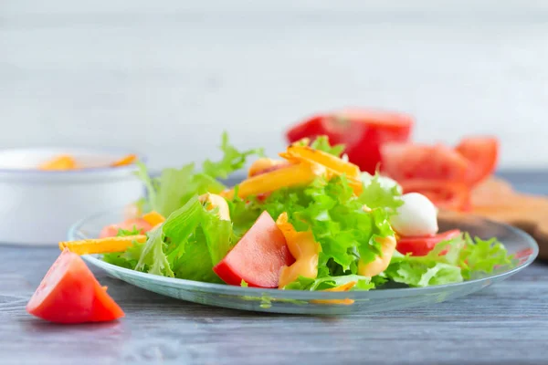 Leaf lettuce salad with tomatoes and crackers on a glass plate.