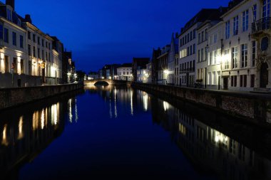 UGES, BELGIUM - 9 Haziran 2017: Şehir merkezindeki antik binalar geceleri kanalların suyuna yansıyor.