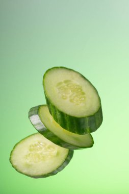 Yeşil arka planda salatalık parçaları ve eğimli salatalık parçaları..