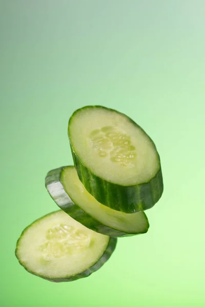 Pieces of cucumber with a snous fall on a green background with a gradient. — Stock Photo, Image