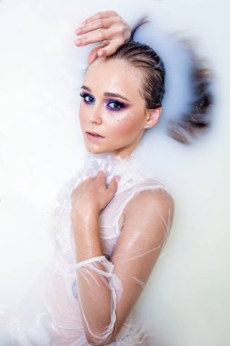 Sütle yıkanan bir kız, rahatlamış hissediyor ve bundan hoşlanıyor, süt cildini daha yumuşak ve kadife gibi yapıyor.