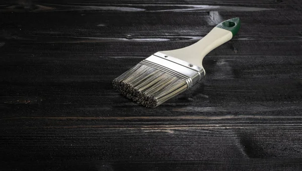 Paint brushes on dark ebony wood desk surface