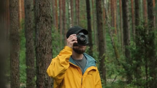 Manlig fotograf fotograferar i en skog på hösten. — Stockvideo