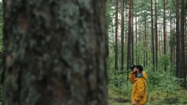 Мужчина-фотограф фотографирует в лесу осенью. — стоковое видео