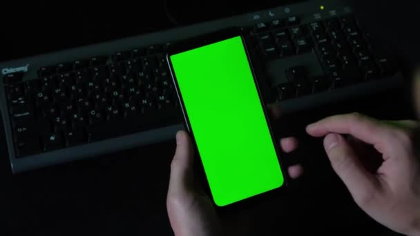 Een jongeman gebruikt een smartphone met groen scherm. Handgebaren aan de telefoon. — Stockvideo