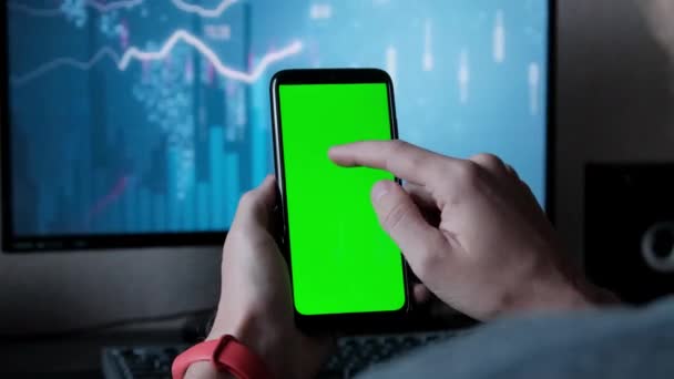 Ένας νεαρός άνδρας κρατώντας μια πράσινη οθόνη ενός κινητού τηλεφώνου στα χέρια των γραφημάτων — Αρχείο Βίντεο