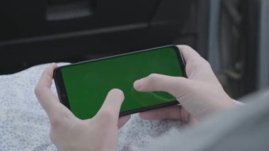 Akıllı telefon kromu tutan bir kadın eli. Anahtar yeşil, boş ekran araba yönü..