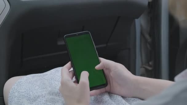 Una mano de mujer sosteniendo un teléfono inteligente croma clave verde pantalla en blanco dirección del coche. — Vídeos de Stock