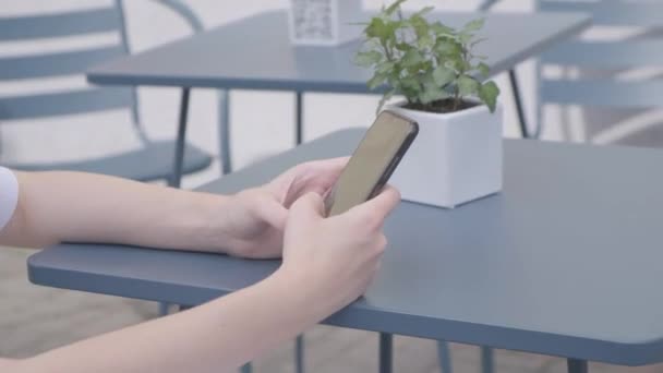 En ung flicka använder smartphone med gester i caféet. Grön skärm. — Stockvideo
