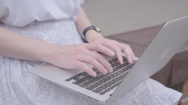 Uma jovem usa um laptop na rua. Fechar tocando no teclado. — Vídeo de Stock