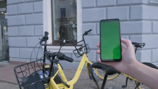 Γυναικεία χέρια κρατώντας μαύρο smartphone με πράσινη οθόνη στο δρόμο της πόλης BG. — Αρχείο Βίντεο