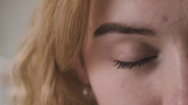 Genç bir kız gözlerini açar ve göz kırpar. Kapalı mavi gözler..