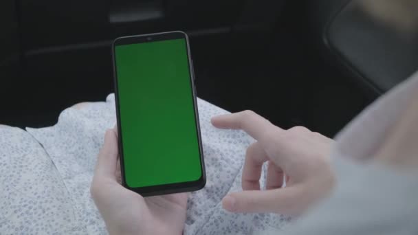 Närbild av en kvinnas hand håller en mobiltelefon grön skärm i bilen — Stockvideo