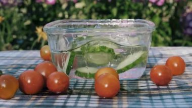 Salatalıklar yavaş çekimde su kabına düşer. Yaz mutfağı.