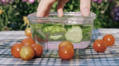 Bir adam ağır çekimde bir kabın içinden salatalıkları alır.