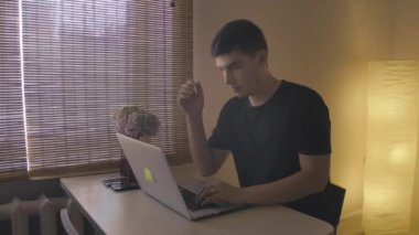 Genç bir adam iş yerindeki iş arkadaşlarıyla video aracılığıyla iletişim kuruyor..