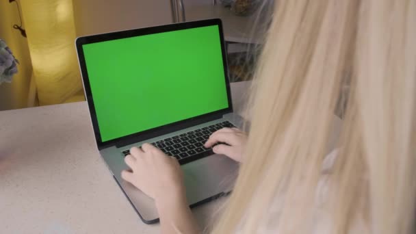Pantalla verde en un portátil. Una joven escribe un mensaje o busca. — Vídeos de Stock