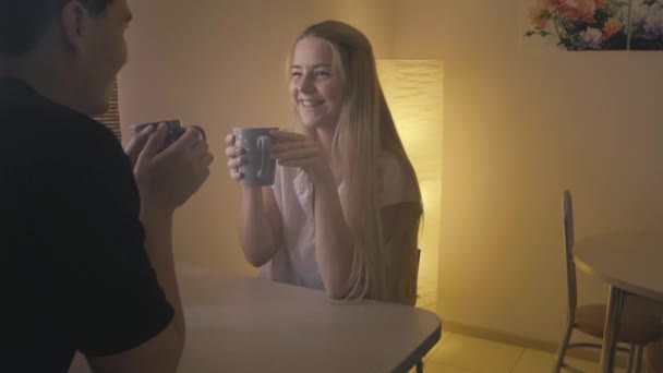 A young couple is drinking tea and chatting at the table. Break after work — Stock Video