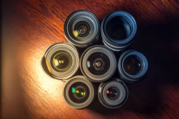 Set of various DSLR lenses with colorful reflections on wooden table — Stock Photo, Image
