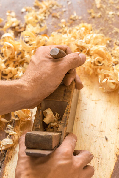 Wooden hand plane. Closeup of woodworkers hands shaving with a plane in a joinery workshop