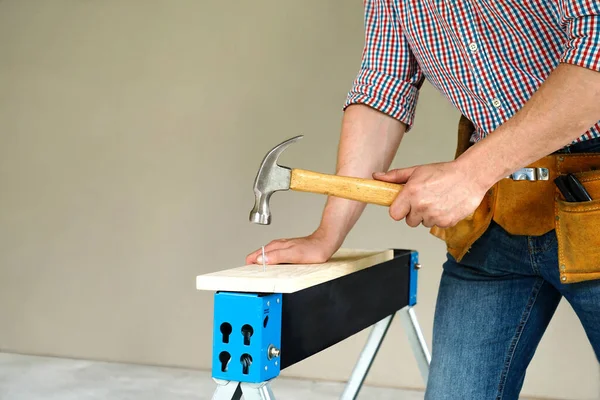 man working with hammer and wood plank. man hammers the nail