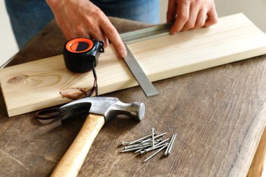 Adam bir tahtayı kare ile ölçer.