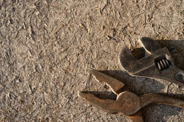 Ahşap arka planda eski paslı ayarlanabilir anahtar ve kerpeten.
