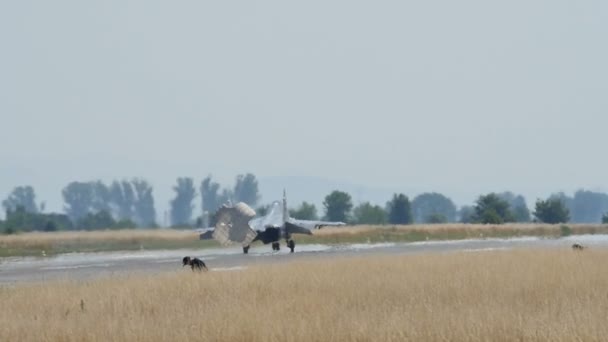 Боевой реактивный самолет на взлетно-посадочной полосе после приземления с открытым медленным парашютом — стоковое видео