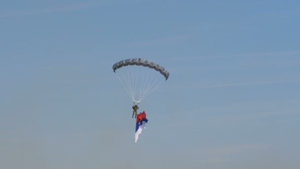 Soldado paracaidista, paracaidista, con bandera serbia durante un desfile militar — Vídeo de stock