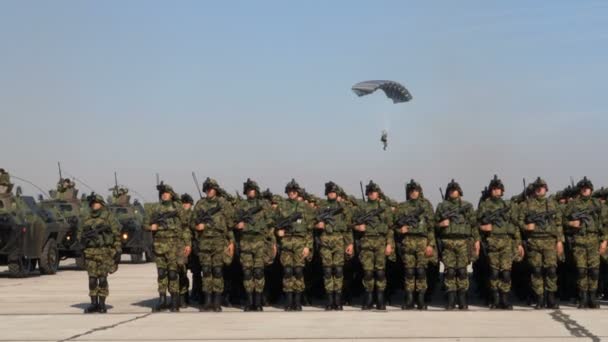Soldatenporträt in grüner Mimetik-Uniform: Fallschirmspringer landet dahinter — Stockvideo