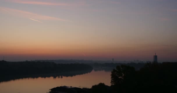 Zeitraffer bei Sonnenaufgang auf der Donau mit Belgrader Gebäuden im Hintergrund — Stockvideo