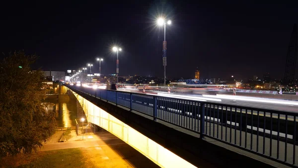 Noční jízdní řády automobilů se světelnými cestami přes most přes řeku Sávu v Bělehradě — Stock fotografie