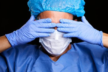 Siyah yalıtılmış arka planda mavi kağıt virüs koruma maskesi takan yorgun, yakışıklı beyaz bir doktorun portresi.