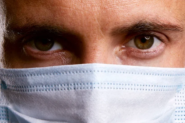 portrait of handsome caucasian doctor man wearing blue paper virus protection mask on black isolated background