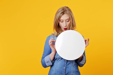 Şaşırdım genç ve güzel beyaz sarışın kadın izole edilmiş sarı arka planda beyaz bir reklam panosu tutuyor.