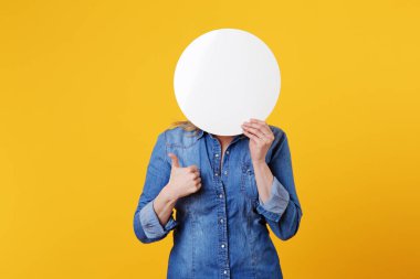 Genç ve güzel beyaz sarışın kadın, sarı arka planda beyaz bir reklam panosu tutuyor.