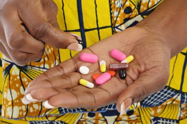 Etnik sarı elbiseli ve elinde uyuşturucu tutan Afrikalı genç bir kadının ellerini kapatın.